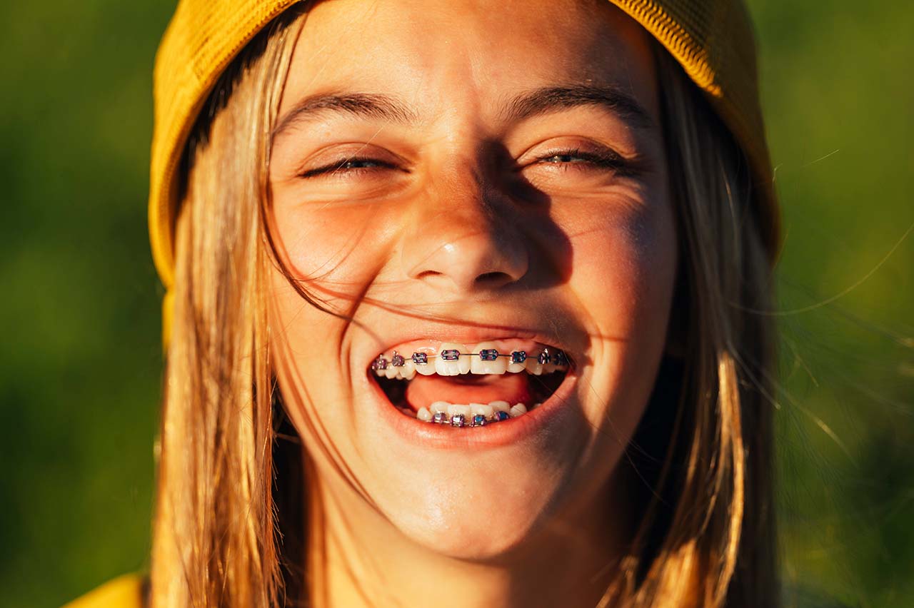 happy teenage girl with a yellow backwards baseball cap Confident teen with braces, living life to the fullest