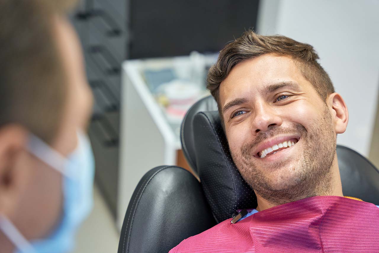 A young man smiling during an initial orthodontic consultation with a dentist.