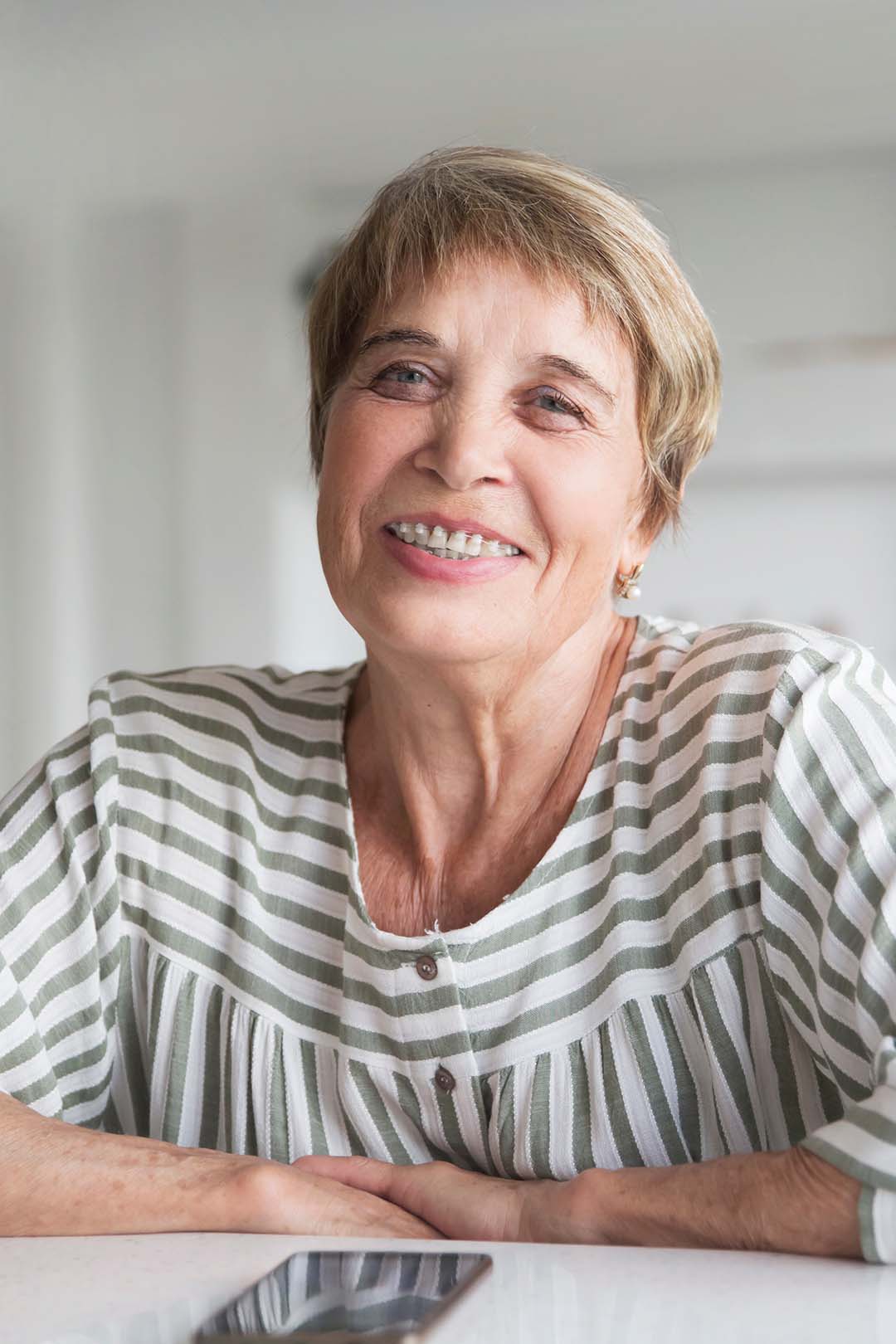 Senior woman with braces smiling at home Ferri Orthodontics treats people of all ages, including seniors