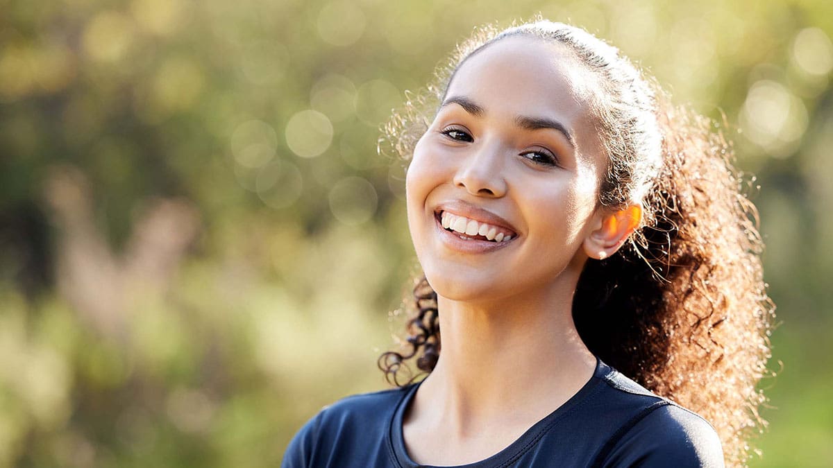 portrait of a confident woman with a big smile outside