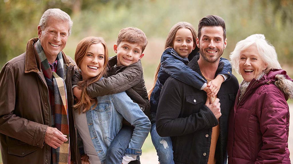 Happy family of all ages smiling together, showcasing the benefits of orthodontic treatment for everyone.